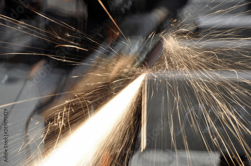 Worker at the factory cuts metal. sparks fly