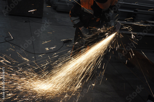 Worker at the factory cuts metal. sparks fly