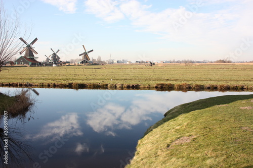 tourist trip to Zaanse schans on a sunny day, among the typical and characteristic windmills of Holland and its waterways