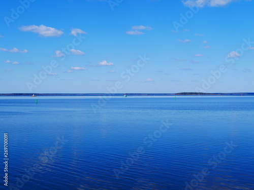 white clouds in the blue sky reflected on the surface of calm water
