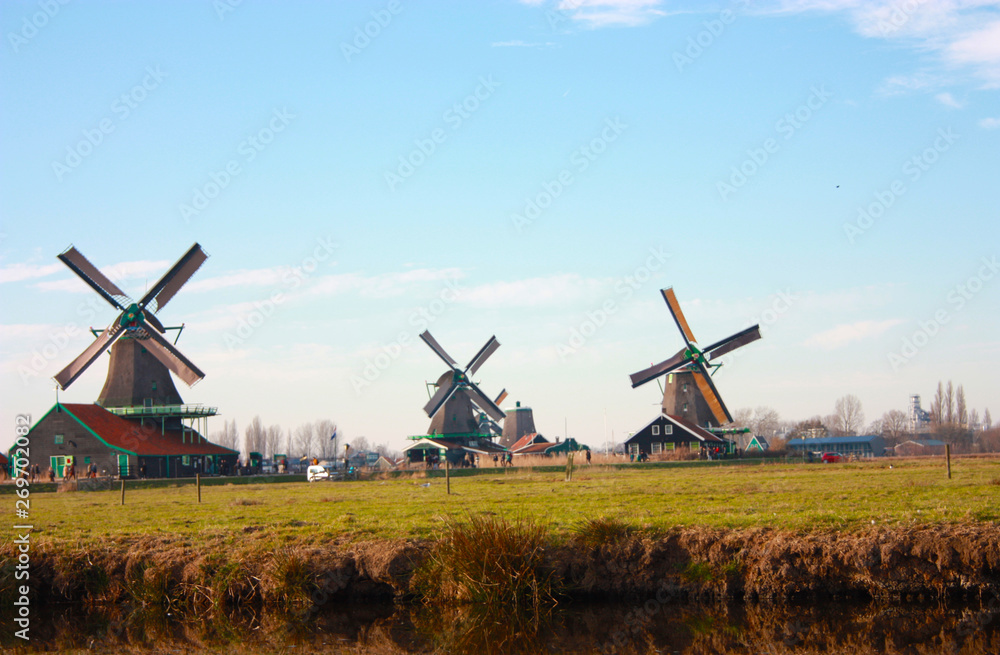tourist trip to Zaanse schans on a sunny day, among the typical and characteristic windmills of Holland and its waterways