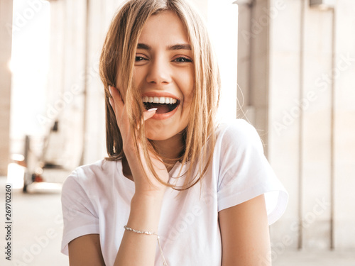 Portrait of beautiful smiling blond model dressed in summer hipster clothes. Trendy girl posing in the street background. Funny and positive woman having fun