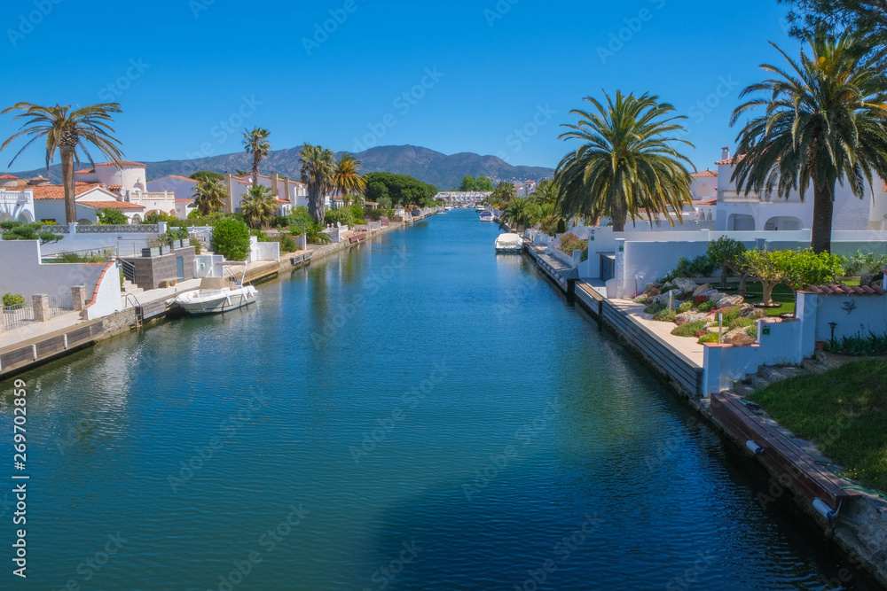 Amazing view on marine canal with boats and houses. Resort town landscape with palm trees, little Spanish Venice, Empuriabrava. Rich lifestyle, Summer time.