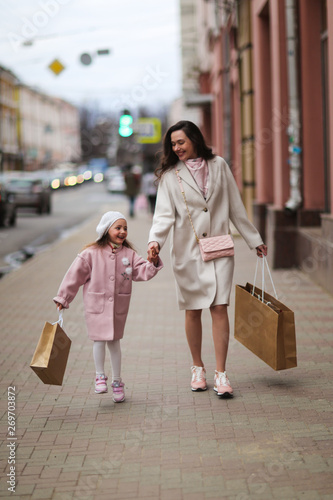 Mom and daughter go shopping down street together