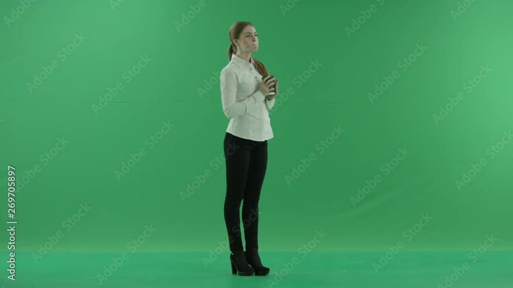 business woman is drinking a cup of coffee or tea. She wears formal dress: white shirt and blak trousers. Businesswoman think, got idea and smile over green screen business woman is drinking a cup of coffee or tea. She wears formal dress: white shirt and blak trousers. Businesswoman think, got idea and smile over green screen
