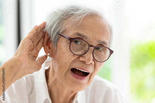 Asian senior woman listening by hand’s up to the ear,having difficulty in hearing,elderly woman hard to hear,wear glasses with hearing impairment,hearing impaired old people
