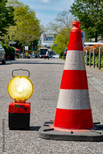Flashing beacon and white-red cone on asphalt