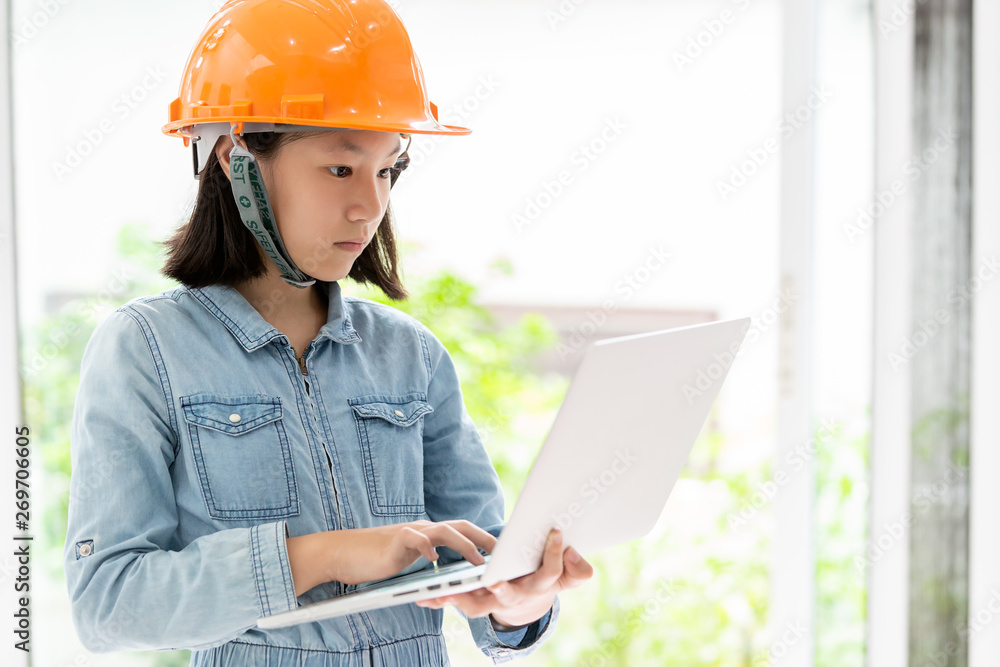 Asian little girl wearing orange safety helmet or hard hat as