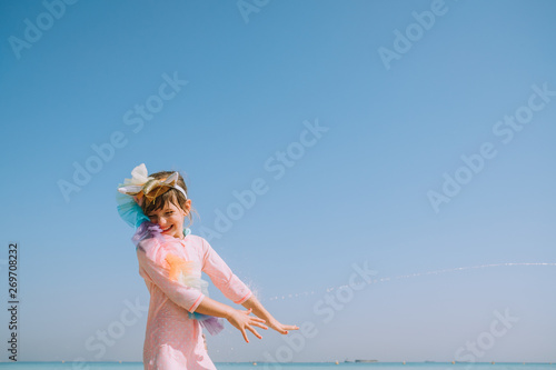 Beautiful girl in unicorn costume laughing at the beach