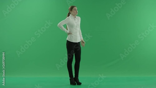 a thoughtful woman is waiting and loking at her whatch . She wears formal dress: white shirt and blak trousers. Businesswoman think, got idea over green screen photo