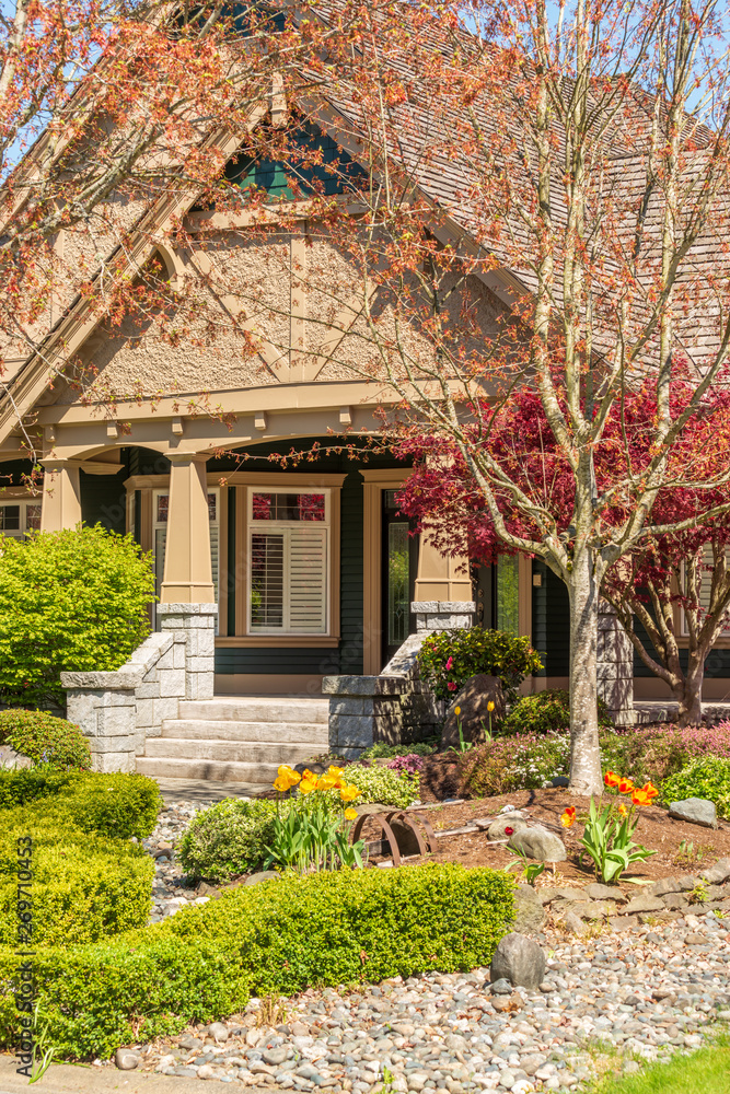 Fgrament of beautiful exterior of newly built luxury home. Yard with green grass and landscape.