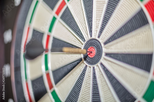 Accurate dart sight hitting center of target, dartboard and dart, blurred background