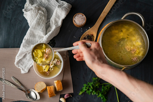 chefs hand pour fresh hot soup in a white empty bowl, food preparations