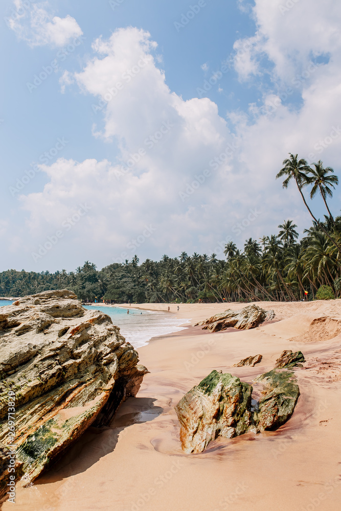 White and rose sand & blue water in Tangalle. Amanwella beach with thin palm trees in the southern province of Sri Lanka. Majestic bay in Indian Ocean. Waves breaking on the most beautiful stones. White and rose sand & blue water in Tangalle. Amanwella beach with thin palm trees in the southern province of Sri Lanka. Majestic bay in Indian Ocean. Waves breaking on the most beautiful stones.
