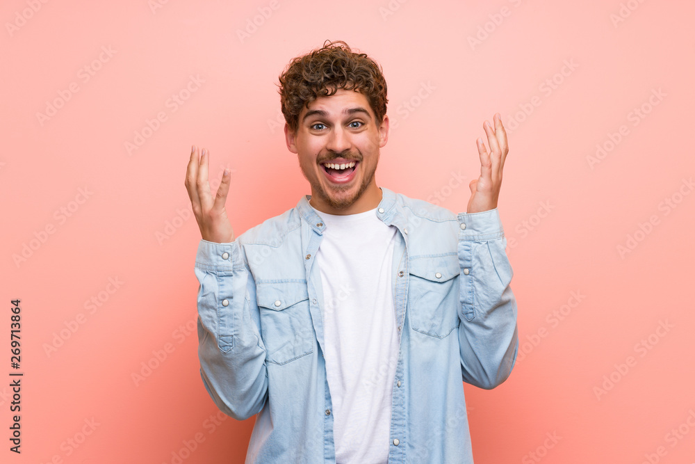 Blonde man over pink wall smiling with a sweet expression Blonde man over pink wall smiling with a sweet expression