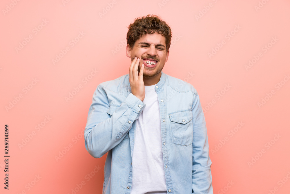Blonde man over pink wall with toothache Blonde man over pink wall with toothache