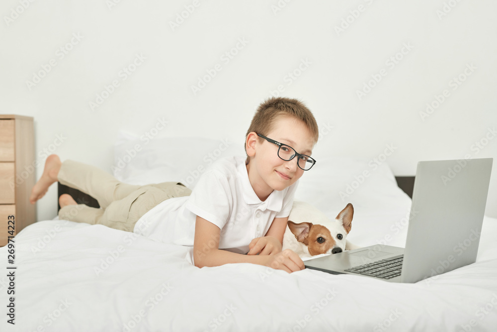 boy with dog jack russell sitting on a white bed at home boy with dog jack russell sitting on a white bed at home