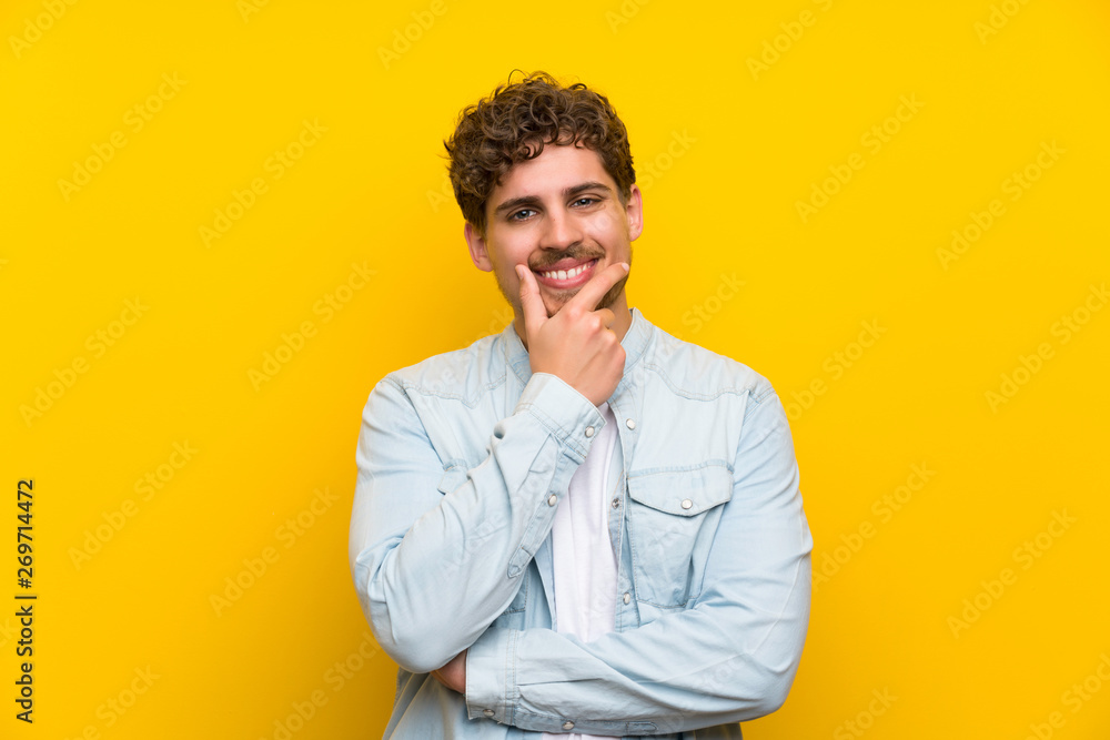 Obraz premium Blonde man over isolated yellow wall laughing