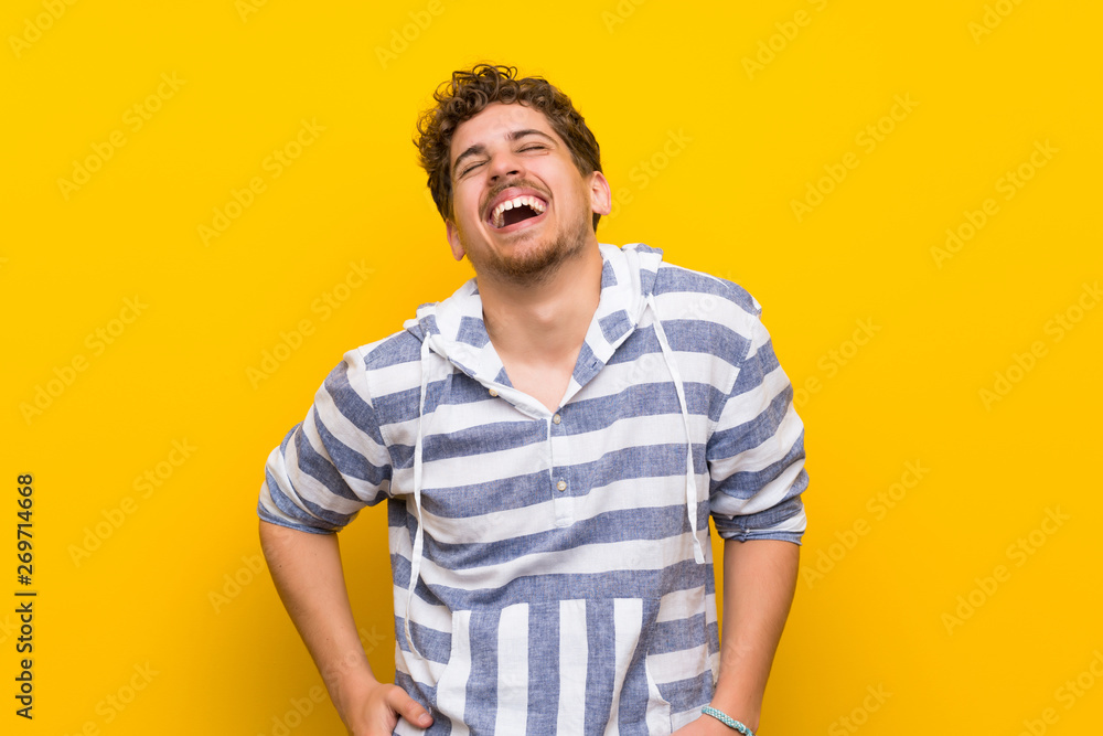 Obraz premium Blonde man over yellow wall happy and smiling