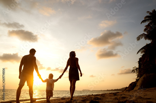 family walk along the beach at sunset with his son: back view silhouette