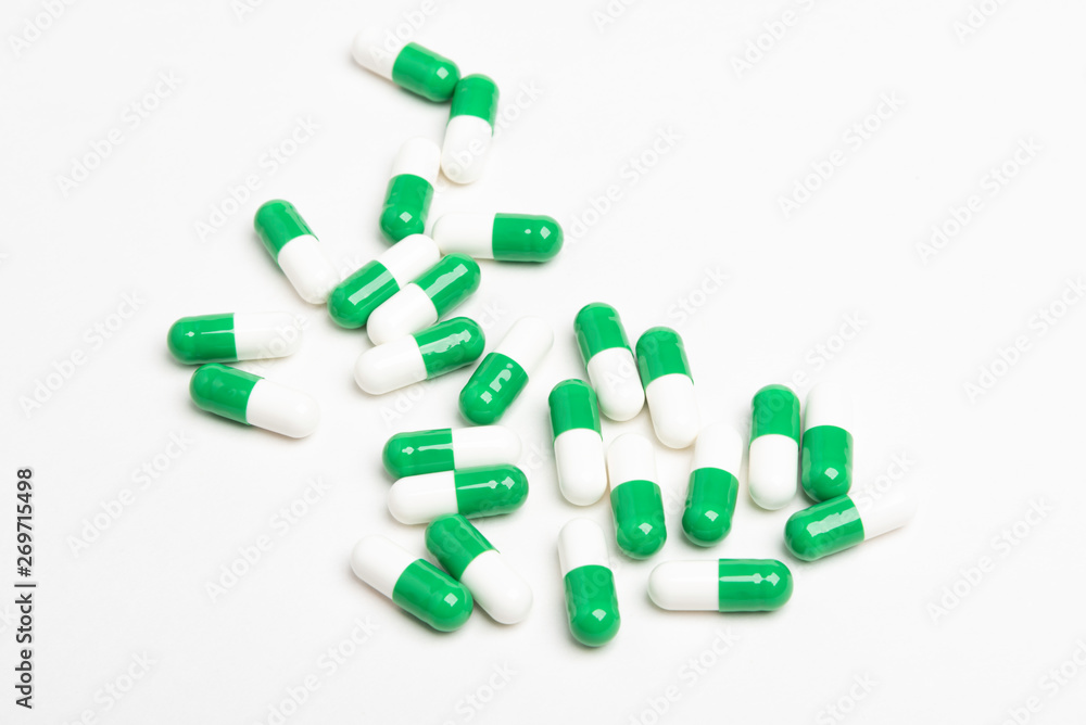 A bunch of green and white medicine capsules artistically set on a plain white background. A bunch of green and white medicine capsules artistically set on a plain white background.