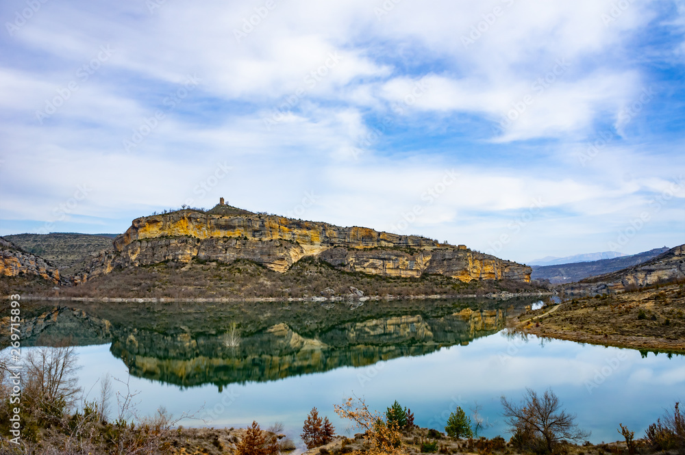 Grey and yellow beautiful mountain cliff in a natural park congost de Mont-rebei Monrebey in Spain on the shore of a blue river reflecting gorge. Grey and yellow beautiful mountain cliff in a natural park congost de Mont-rebei Monrebey in Spain on the shore of a blue river reflecting gorge.