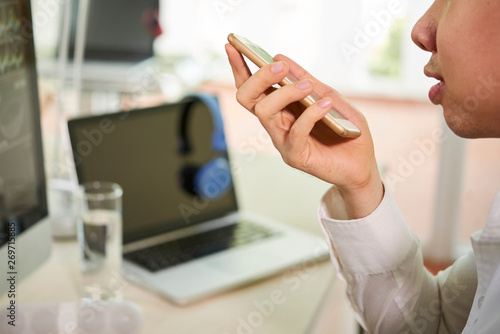 Foto Close-up of young businessman holding mobile phone in his hand and talking on sp