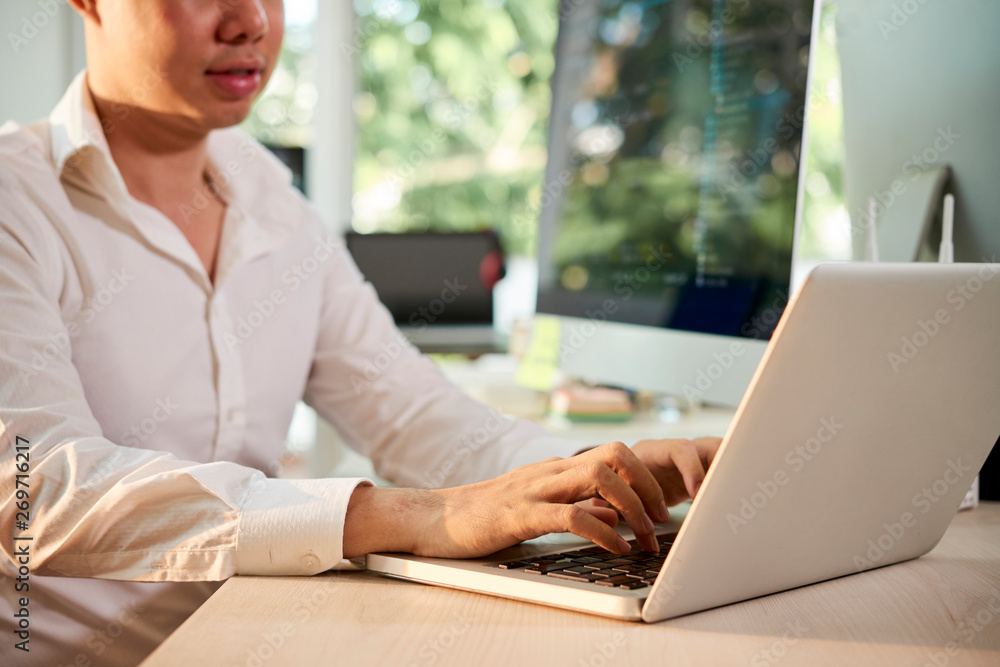 Young businessman sitting at workplace and working online on laptop computer at office Young businessman sitting at workplace and working online on laptop computer at office