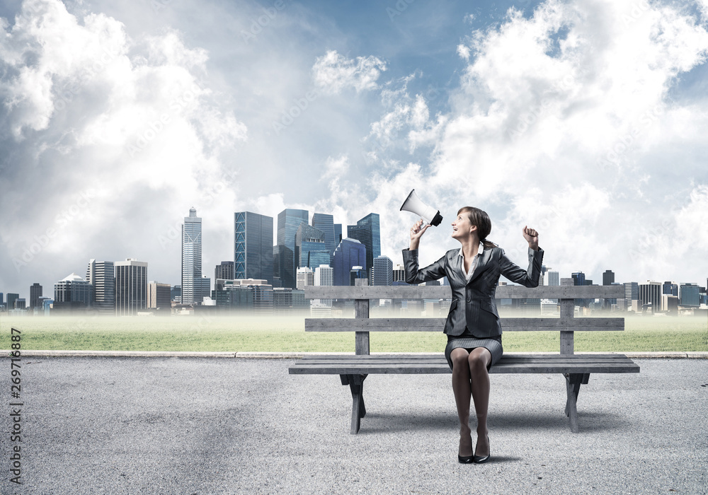 Business woman with megaphone on wooden bench Business woman with megaphone on wooden bench