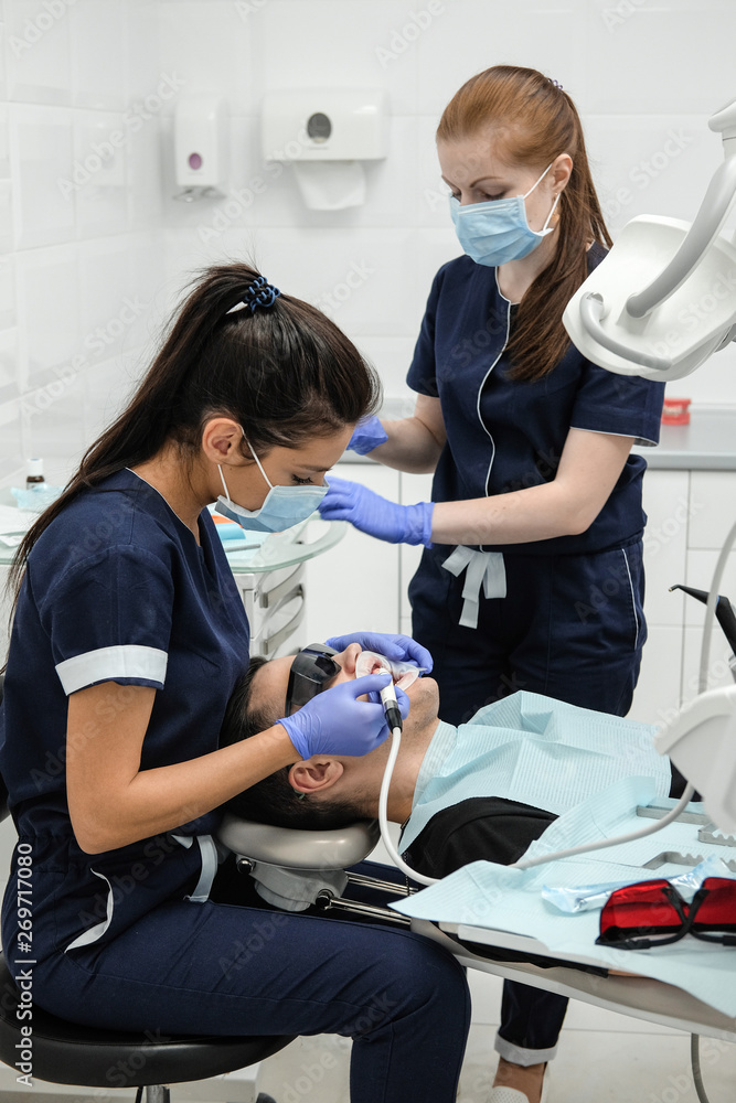 Patient on reception at the dentist. Woman's doctor sets up equipment before dental treatment. Patient on reception at the dentist. Woman's doctor sets up equipment before dental treatment.
