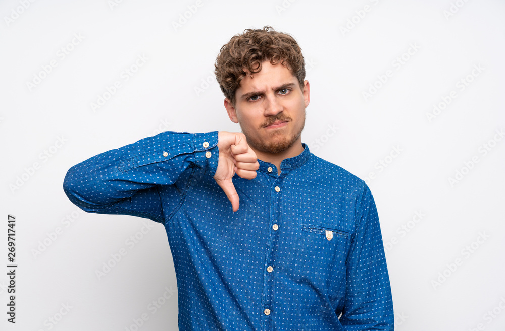 Blonde man with blue shirt showing thumb down sign Blonde man with blue shirt showing thumb down sign