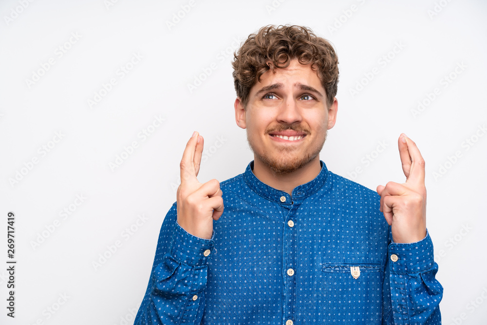 Blonde man with blue shirt with fingers crossing
