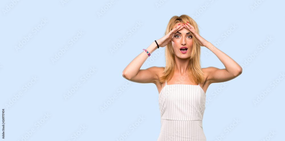 Young blonde woman with surprise expression over isolated blue background Young blonde woman with surprise expression over isolated blue background