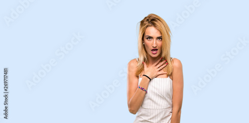 Young blonde woman surprised and shocked while looking right over isolated blue background
