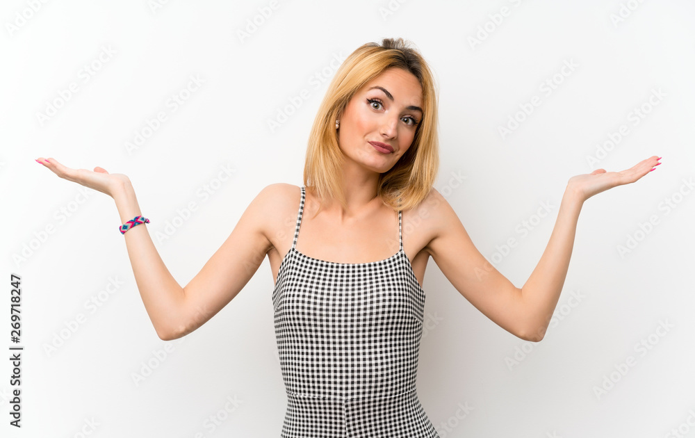 Young blonde woman over isolated white making doubts gesture Young blonde woman over isolated white making doubts gesture
