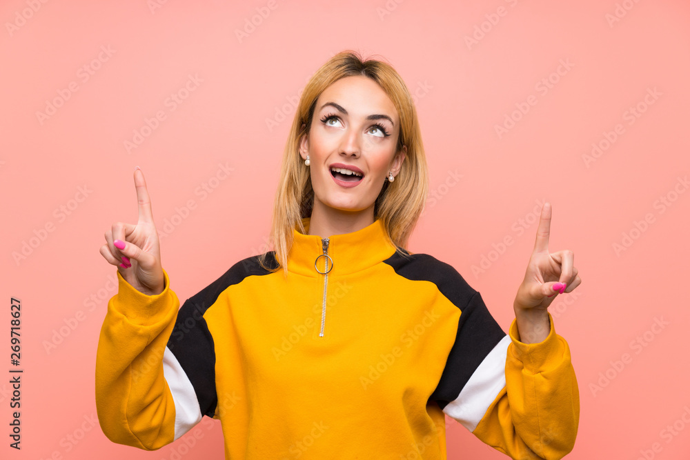 Young blonde woman over isolated pink background surprised and pointing up Young blonde woman over isolated pink background surprised and pointing up