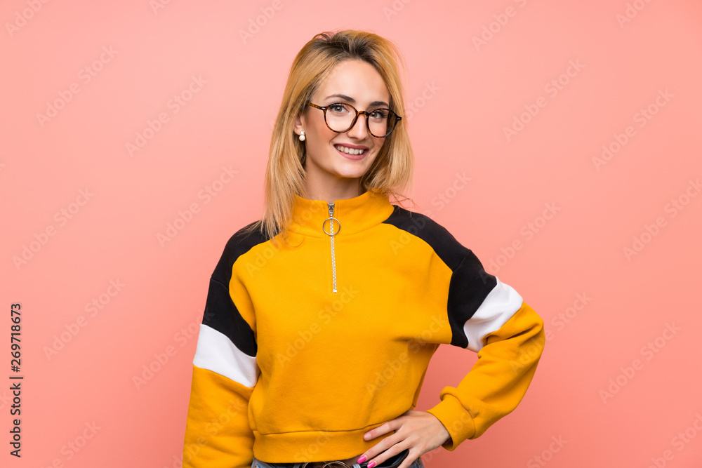 Young blonde woman over isolated pink background with glasses and smiling Young blonde woman over isolated pink background with glasses and smiling