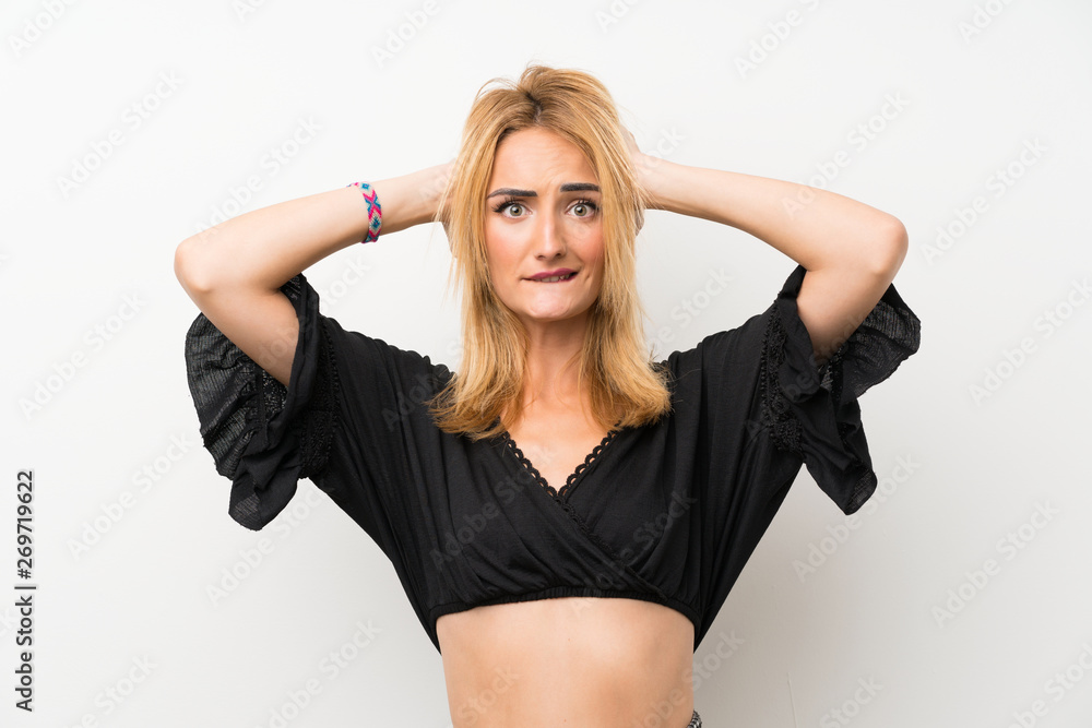 Young blonde woman over isolated white wall frustrated and takes hands on head Young blonde woman over isolated white wall frustrated and takes hands on head