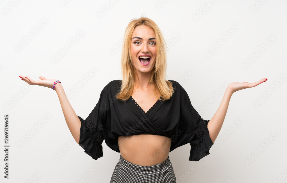 Young blonde woman over isolated white wall with shocked facial expression Young blonde woman over isolated white wall with shocked facial expression