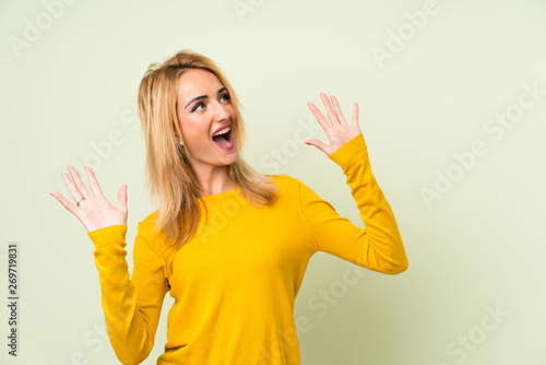 Young blonde woman over isolated green background with surprise facial expression