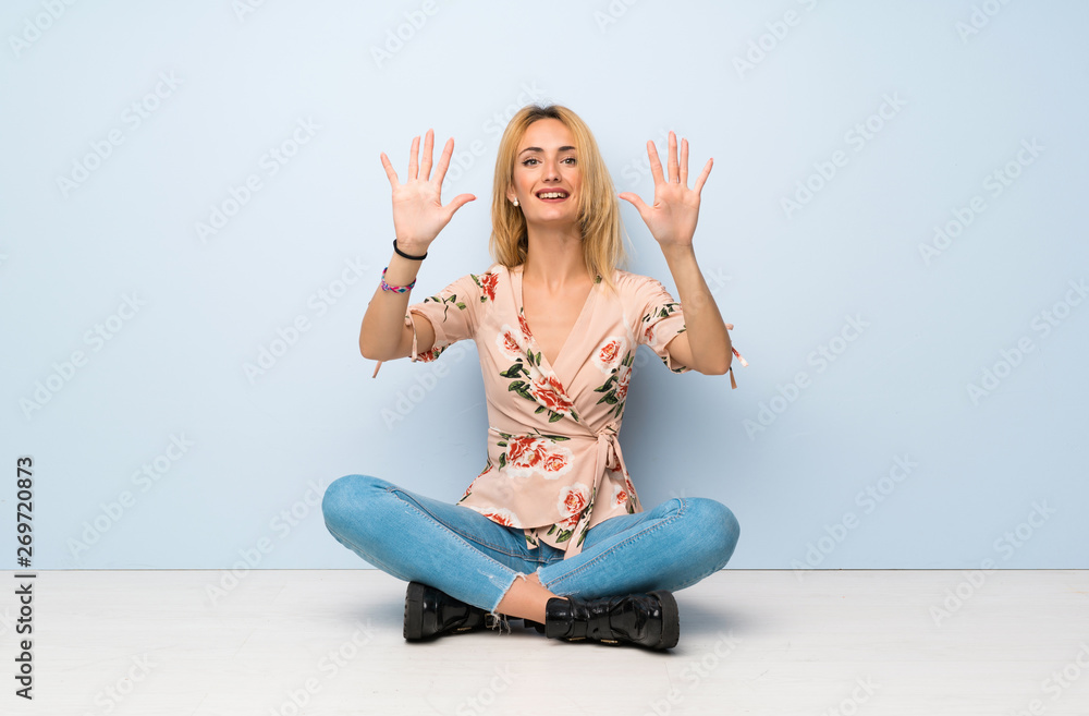 Young blonde woman sitting on the floor counting ten with fingers Young blonde woman sitting on the floor counting ten with fingers