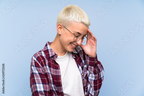 Teenager girl with white short hair over blue wall laughing