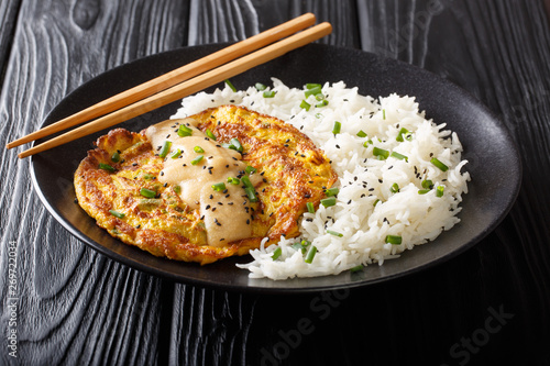 Portion of fried Chinese omelet Egg Foo Young served with a side dish of white rice close-up on a plate. Horizontal photo