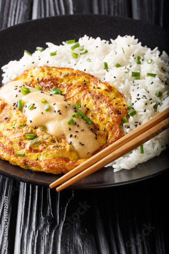 Crispy fluffy egg foo young filled with crisp veggies and aromatic green onion and served with a rice close-up. vertical photo