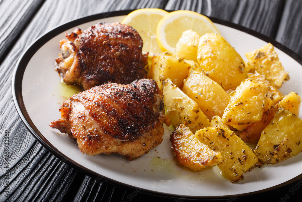 Greek lemon potatoes with garlic and herbs served with chicken thigh grilled close-up. horizontal Greek lemon potatoes with garlic and herbs served with chicken thigh grilled close-up. horizontal