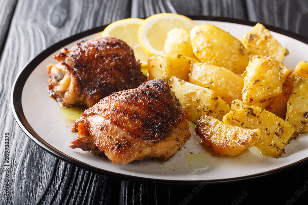 Main course: grilled chicken thighs served with delicious lemon garlic potatoes closeup. horizontal