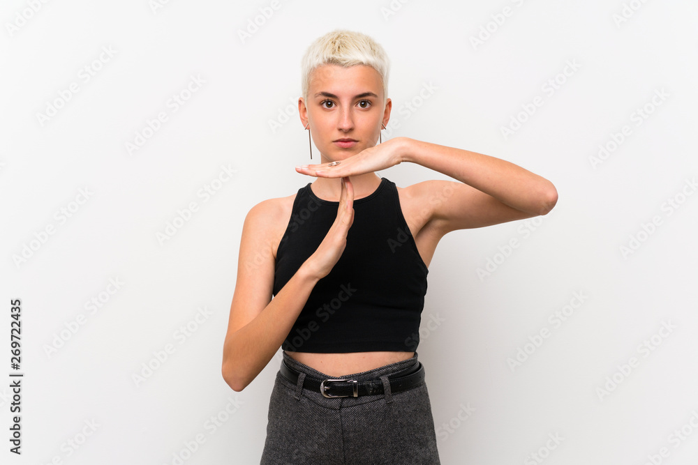 Teenager girl with short hair over white wall making time out gesture Teenager girl with short hair over white wall making time out gesture