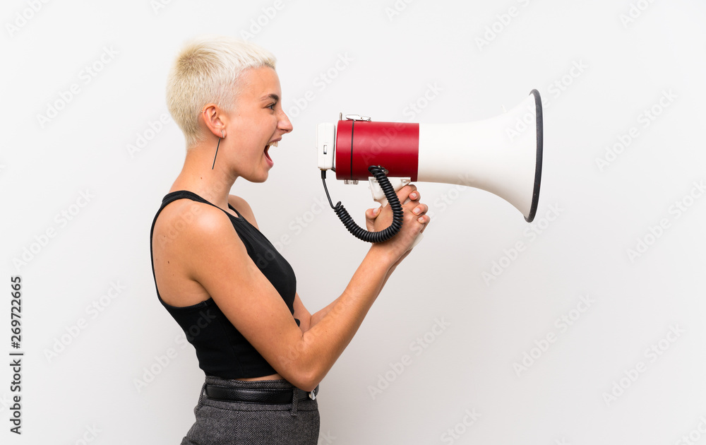 Naklejka premium Teenager girl with short hair over white wall shouting through a megaphone