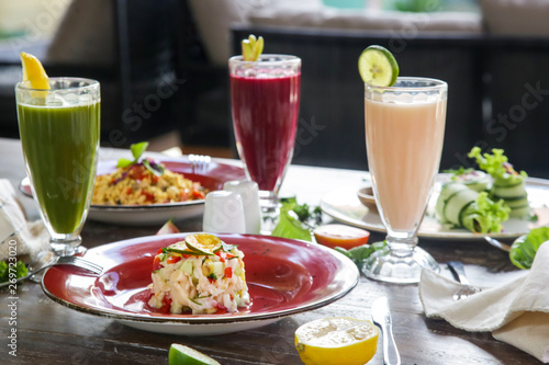 Healthy organic vegetarian dishes and glasses of detox drinks served on the restaurant table. 