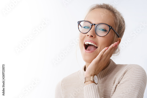 Absolutely happy. Studio shot of amused and excited carefree joyful woman relaxing having fun singing and smiling cheerful touching cheek raising head dancing against white background happily